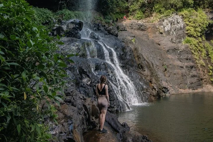 Eine Frau steht auf Felsen und betrachtet einen mehrstufigen Wasserfall
