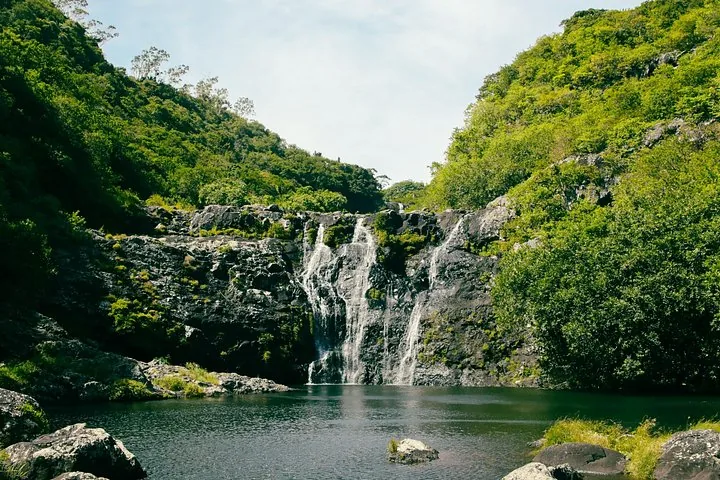 Una cascada ancha que cae en una poza serena rodeada de denso bosque
